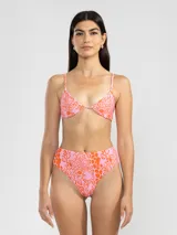 Conjunto de bikini de lycra estampada con motivos abstractos en tonos rosados y anaranjados. El corpiño es de corte triangular con tirantes finos y la bombacha es de tiro alto.