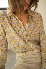 Camisa de seda de corte clásico con cuello camisero, cierre frontal de botones y mangas largas con puños. Presenta un estampado floral multicolor con tonos pasteles sobre fondo claro.