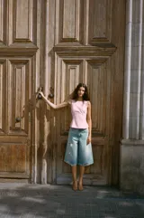 Top rosado de escote recto con tirantes finos que se anudan en la parte superior. Presenta costuras que realzan la figura y cierre con cremallera oculta en la costura lateral.