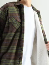 Sobrecamisa de franela a cuadros azul, verde y blanco, con forro de corderito blanco, cuello clásico, cierre frontal con botones, mangas largas y dos bolsillos con solapa abotonada en el pecho.