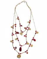 Collar largo de tres vueltas confeccionado en acero, con cadena fina dorada, piedras naturales en tonos rojos y diversos dijes metálicos con formas de flores, hojas y cactus.