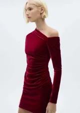 Vestido corto de terciopelo color rojo, con diseño asimétrico de un solo hombro y manga larga. Presenta un detalle de fruncido lateral que aporta un ajuste entallado a la silueta.
