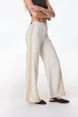 Pantalón de pierna ancha con acabado brillante, confeccionado en lino. Presenta un diseño de tiro medio con cierre de botón y cremallera, bolsillos traseros y etiqueta de marca en la cintura.