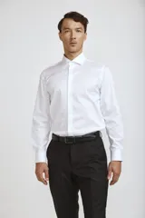 Camisa de vestir blanca de manga larga, con cuello clásico y cierre frontal de botones ocultos.