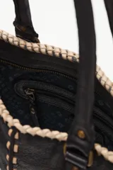 Cartera de mano tipo tote de cuero vacuno negro, con diseño de mariposa en apliques de cuero con estampado animal print. Presenta costuras decorativas en los bordes y en el centro, con doble asa de hombro.