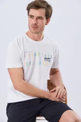 Remera blanca de manga corta y cuello redondo, confeccionada en algodón y poliéster, con estampa frontal multicolor de remos y logo de la marca.