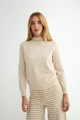 Polera de punto color beige, con cuello alto y mangas largas, de diseño básico y ajuste clásico.