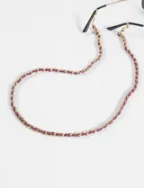 Correa para lentes compuesta por una cadena dorada entrelazada con una tira de microfibra color fucsia, con terminales metálicos para sujeción.