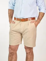 Bermuda color beige confeccionada en lino, con bolsillos laterales y traseros, y presillas para cinturón.