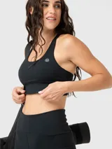 Top deportivo negro de sujeción media con espalda cruzada y diseño ergonómico. Confeccionado en tejido suave con tecnología Aloe Vera.