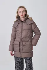 Campera puffer de corte largo y diseño acolchado, color marrón topo. Cuenta con capucha desmontable, cierre frontal con cremallera, cordón ajustable en la cintura y dos bolsillos frontales con solapa.