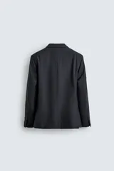 Blazer de corte regular confeccionada en lana de origen italiano, con diseño a cuadros sutiles. Presenta cuello con solapas de muesca, cierre frontal de un botón, bolsillos laterales con solapa y bolsillo en el pecho. Cuenta con aberturas en la espalda y forro interior.