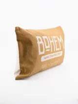 Funda de almohadón rectangular color beige con estampa tipográfica en blanco con la palabra "BOHEM" y la frase "HAND CRAFTED TYPE HUSTLE SUPPLY".
