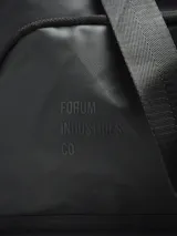 Bolso de viaje color gris oscuro, con múltiples compartimentos exteriores con cierre y elástico. Se puede usar como bolso de mano, mochila o al hombro con tira ajustable. Las tiras tipo mochila son guardables.