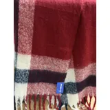 Bufanda rectangular de tejido grueso con diseño de cuadros en tonos azul, naranja, gris y beige, terminada con flecos en los extremos.