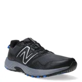 Championes de running New Balance modelo 410, color negro con detalles en gris y azul. Presentan una construcción en malla transpirable y refuerzos sintéticos, con el logo N característico en los laterales y una suela de alto rendimiento diseñada para ofrecer tracción y amortiguación.