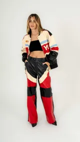 Pantalón de cuero sintético negro con paneles en rojo y beige.