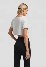 Remera cropped de algodón, color gris claro, con cuello redondo y manga corta doblada. Presenta un estampado frontal de un plátano amarillo.