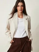 Blazer beige claro de corte recto, con solapas de muesca, mangas largas y bolsillos frontales.
