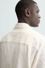 Camisa de corte relajado confeccionada en tejido de algodón con diseño jacquard floral. Presenta cuello bowling, manga corta, un bolsillo de parche en el pecho y aberturas laterales en el bajo. Cierre frontal con botones al tono.