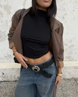 Cinturón trenzado de cuero negro con hebilla metálica circular grande de estilo western.