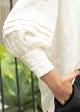 Blusa color crudo confeccionada en lino de alto gramaje, con cartera frontal con puntilla y caída natural.