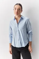Camisa de algodón blanca, de calce relajado, con cuello clásico, mangas largas y cierre frontal con botones.