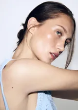 Chaleco celeste de punto con diseño de flores perforadas, sin mangas, escote redondo y cierre frontal con botones.
