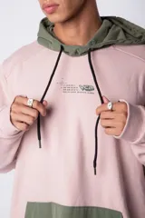 Buzo tipo canguro con capucha, confeccionado en una combinación de algodón rústico y microfibra. Presenta un diseño bicolor en tonos rosado y verde militar, con bolsillo frontal tipo canguro en contraste, cordones ajustables y estampa personalizada en el frente.