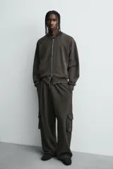 Pantalón cargo de corte relajado con efecto lavado, confeccionado en tejido de algodón. Presenta cintura elástica, bolsillos laterales de plastrón con solapa y bolsillos delanteros.