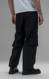 Pantalón cargo de corte oversize y silueta estructurada, confeccionado en microfibra pesada con leve elasticidad. Presenta cintura elástica con cordón de ajuste externo, cierre frontal con botón metálico, bolsillos laterales y bolsillos cargo de gran tamaño con tapa y broches a presión.