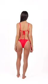 Conjunto de bikini rojo, compuesto por un corpiño triangular con tiras finas ajustables que se atan al cuello y a la espalda, y una bombacha de corte clásico con laterales regulables con tiras.