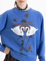 Buzo de cuello redondo y manga larga, color azul con estampa frontal de cisnes y flores. Presenta un calce amplio y largo a la cadera.
