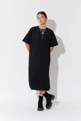 Vestido largo de manga corta y corte oversize, confeccionado en tejido con textura. Presenta cuello redondo y un parche decorativo en la parte posterior.