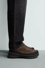 Zapatilla de cordones con parte superior de piel con acabado serraje, horma redonda, suela con volumen y piso track.