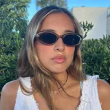 Lentes de sol con armazón ovalado de estilo retro en color negro y cristales oscuros. Presentan un detalle metálico en forma de estrella en las patillas.