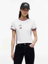 Remera de algodón Tommy Hilfiger en colaboración con Cadillac Formula 1 Team, de corte holgado y largo cropped. Presenta cuello redondo con ribetes tricolores, mangas cortas con ribetes a juego y cinta distintiva en los laterales. Incluye logos de Cadillac, Tommy Hilfiger y Pirelli estampados en el pecho y mangas.