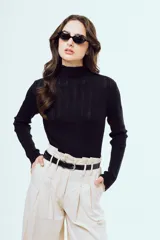 Top de punto negro con cuello alto, diseño al cuerpo y mangas largas, confeccionado con textura acanalada.