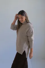 Polerón de cuello alto con diseño de rombos tejidos en relieve, mangas largas con puños acanalados y ruedo también acanalado.