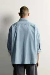 Camisa regular fit de denim de algodón con efecto lavado, cuello solapa y manga larga con puño abotonado. Tiene un bolsillo de parche en el pecho con detalle bordado a contraste y cierre frontal con botonadura.