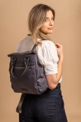 Cartera mochila de diseño versátil, color rosado, confeccionada en material sintético impermeable. Cuenta con doble asa superior, correas ajustables para usar como mochila, compartimento principal con cierre y bolsillo frontal con cierre decorado con tirador largo.