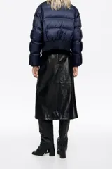Chaqueta acolchada de corte globo en tejido técnico color azul marino, con cierre frontal de cremallera y botones a presión, maxicuello de punto acanalado, manga larga con puño elástico y bajo de punto.