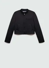 Chaqueta corta de diseño recto, color negro, con cuello de tira, cierre frontal con cremallera, bolsillos laterales y un bolsillo de ribete en el pecho.