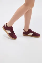 Zapatillas urbanas de color negro con suela de goma marrón, cordones negros con detalles blancos y paneles laterales.