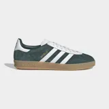 Championes Adidas Gazelle Indoor de color verde oscuro con las tres tiras laterales blancas y suela de goma color caramelo. Presentan un exterior de cuero con detalles sintéticos, cordones blancos y el nombre del modelo grabado en dorado.