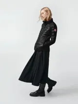 Campera acolchada de diseño técnico, color negro, con cierre frontal completo y cuello alto. Presenta paneles laterales elásticos para mayor movilidad y un acabado brillante en el cuerpo principal.