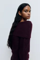 Buzo de punto trenzado con escote estilo off-the-shoulder y cuello ancho acanalado. Presenta mangas largas y terminaciones en punto acanalado en puños y bajo.