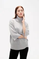 Polera de tejido de punto color gris, con cuello alto, mangas 3/4 y diseño holgado.