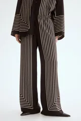 Pantalón de tiro alto con cintura elástica, piernas rectas y diseño estampado de líneas blancas que forman un marco geométrico en la parte inferior sobre fondo negro.