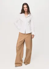 Camisa entallada de popelín de algodón en color blanco, con cuello camisero, manga larga con puños anchos abotonados y cierre frontal oculto.
